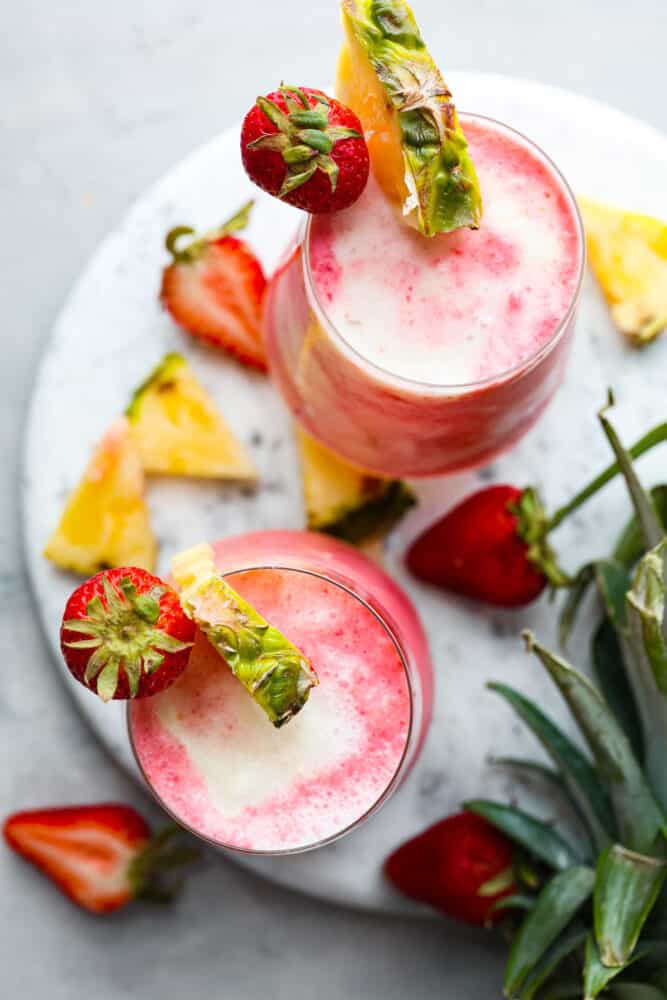 This fruity drink is a version of the Lava Flow cocktail that the whole family can enjoy! It's creamy and refreshing with delicious coconut, pineapple, and strawberry in each sip. Top-down view of 2 lava flow cocktails.