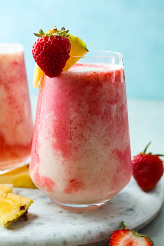 This fruity drink is a version of the Lava Flow cocktail that the whole family can enjoy! It's creamy and refreshing with delicious coconut, pineapple, and strawberry in each sip. Closeup of a frozen strawberry coconut cocktail.