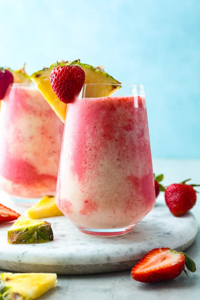 This fruity drink is a version of the Lava Flow cocktail that the whole family can enjoy! It's creamy and refreshing with delicious coconut, pineapple, and strawberry in each sip. Hero image of 2 glasses filled with the lava flow cocktail.