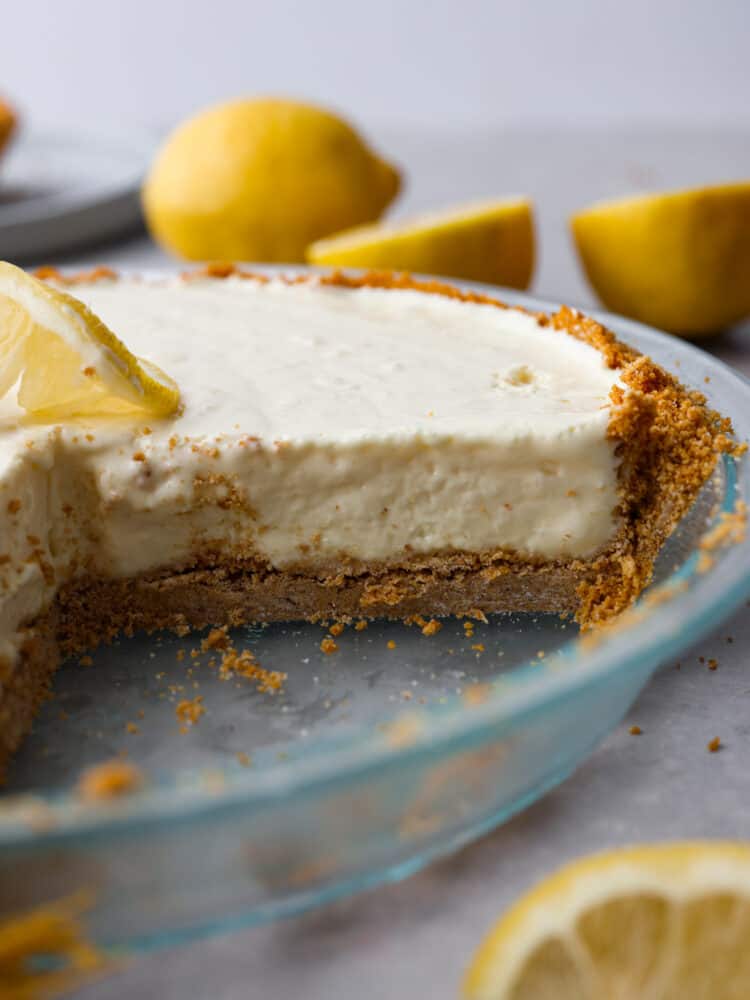 Meet your new favorite summer dessert! This lemonade pie has a buttery graham cracker crust, topped with a creamy lemonade filling thatโs the perfect balance of tangy and sweet. Itโs served chilled, so itโs great for cooling you down and satisfying your sweet tooth all at the same time. A whole lemonade pie with a slice cut out of it.