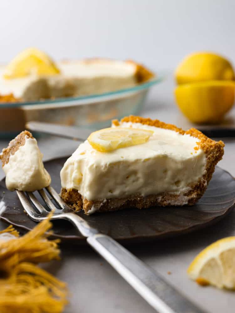 Meet your new favorite summer dessert! This lemonade pie has a buttery graham cracker crust, topped with a creamy lemonade filling thatโs the perfect balance of tangy and sweet. Itโs served chilled, so itโs great for cooling you down and satisfying your sweet tooth all at the same time. A slice of pie with a bite taken out of it.