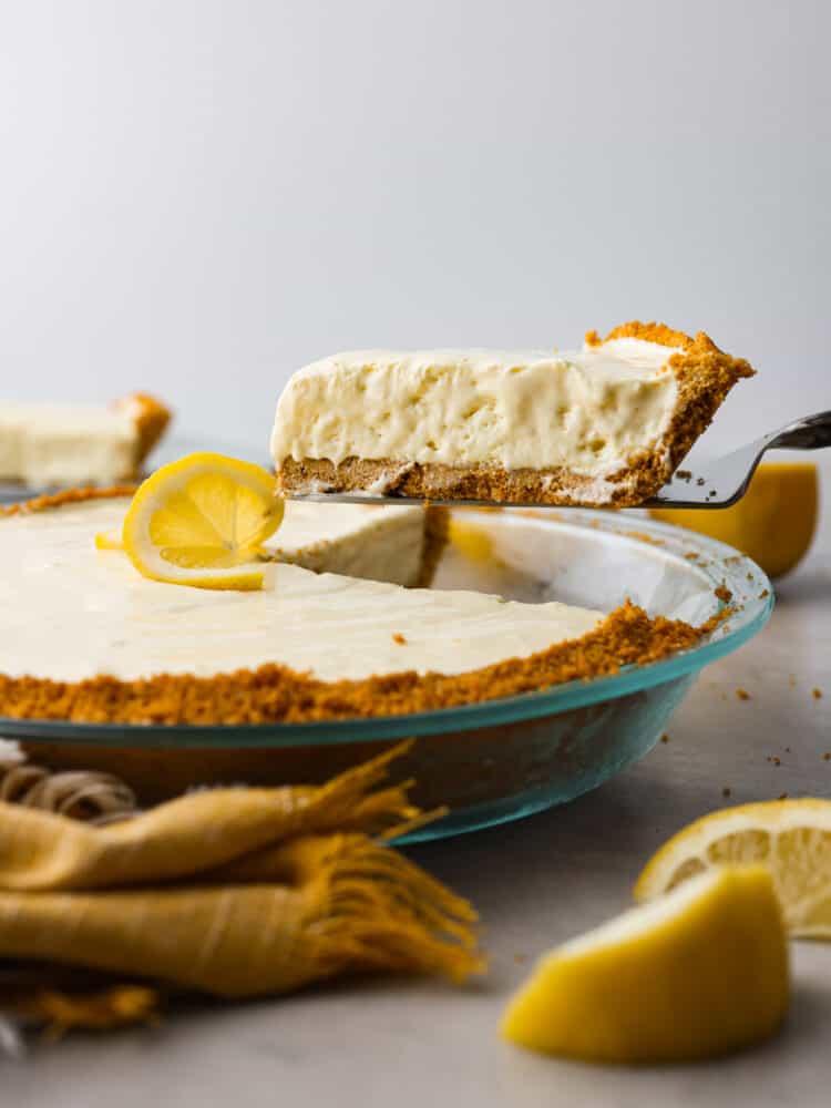 Meet your new favorite summer dessert! This lemonade pie has a buttery graham cracker crust, topped with a creamy lemonade filling thatโs the perfect balance of tangy and sweet. Itโs served chilled, so itโs great for cooling you down and satisfying your sweet tooth all at the same time. A slice of lemonade pie being served.