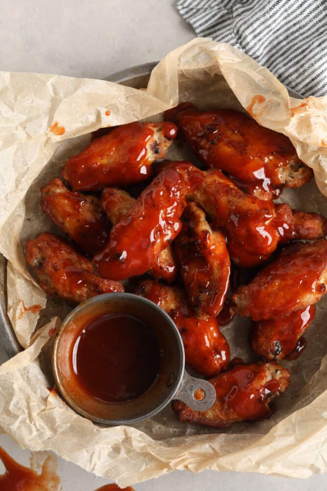 Mumbo sauce is like a dreamy combination of barbecue and sweet and sour sauce. It’s tangy and savory with a glaze-like texture that’s wonderful for coating chicken wings! Top-down view of sauced chicken wings.