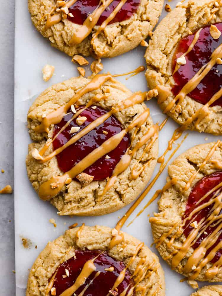 A classic flavor pairing, but in cookie form! These peanut butter and jelly cookies are extra soft and delicious, each with a strawberry jam core and peanut butter drizzle on top. Hero image of peanut butter and jelly cookies.