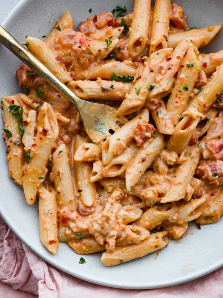 This ultra-delicious Pink Sauce Pasta recipe features penne pasta cooked al dente and tossed in a flavorful pink sauce. The dish is garnished with fresh basil and grated parmesan cheese for an extra touch of deliciousness. Pink sauce pasta on a plate with a fork.