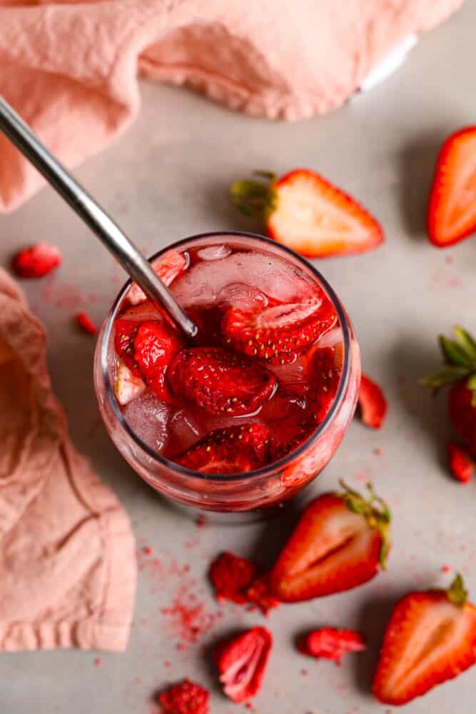 This Strawberry Acai Refresher is a refreshing drink that's sure to help you beat the heat! Whether you're lounging by the pool, hosting a summer soirรฉe, or simply in need of a tropical escape, this refresher will be your go-to beverage. The top view of a strawberry acai refresher. You can see into the cup with ice and strawberries at the top.