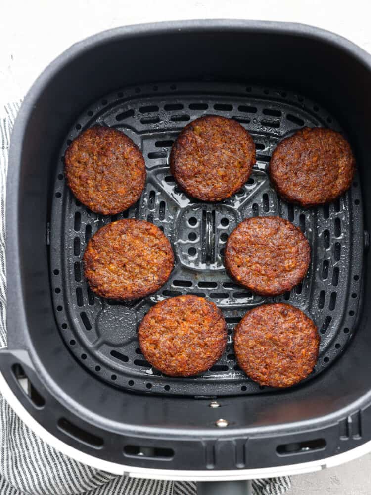 For a quick and delicious breakfast, try making frozen sausage patties in the air fryer! In less than 10 minutes they turn tender and juicy, perfect for adding to your favorite English muffins! Cooked sausage patties in the basket of an air fryer.