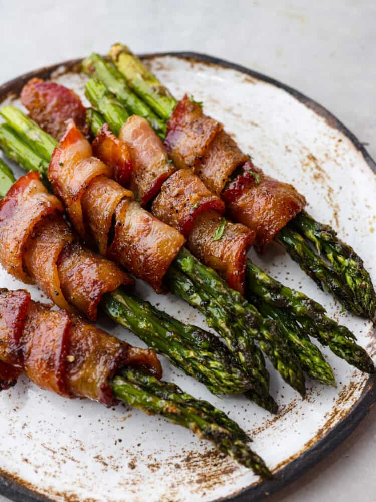 Bacon wrapped asparagus is a smoky and savory side dish that will be a staple for mealtime. Each bundle is glazed with maple syrup for caramelized flavor you wonโt be able to get enough of! Closeup of cooked bundles.