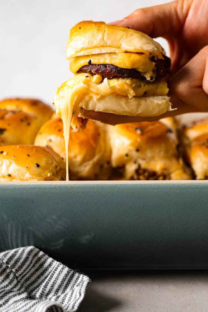 For a quick and delicious breakfast, try making frozen sausage patties in the air fryer! In less than 10 minutes they turn tender and juicy, perfect for adding to your favorite English muffins! A sausage, egg, and cheese sandwich being picked up.