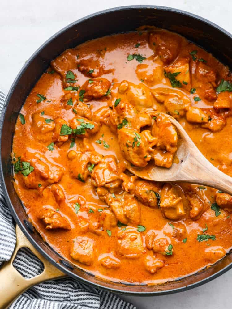 If you've never had butter chicken, you're in for a treat! This classic Indian dish takes chicken thighs and simmers them in a creamy tomato sauce packed with spices until the chicken is irresistibly tender. Serve over steamed jasmine rice with some warm naan bread! Top-down view of butter chicken in a skillet.