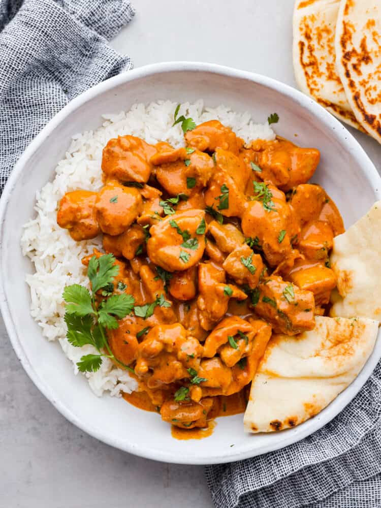 If you've never had butter chicken, you're in for a treat! This classic Indian dish takes chicken thighs and simmers them in a creamy tomato sauce packed with spices until the chicken is irresistibly tender. Serve over steamed jasmine rice with some warm naan bread! Butter chicken served over white rice with naan.