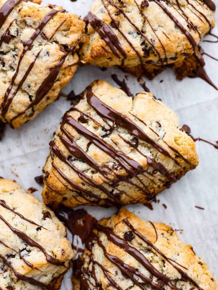 Chocolate chip scones are downright delicious. Theyโre buttery and soft, with pockets of chocolate chips for a melty surprise in each bite. These homemade scones are great for an on-the-go breakfast or an afternoon snack when youโre craving something sweet! Top-down view of chocolate chip scones, drizzled with melted chocolate.