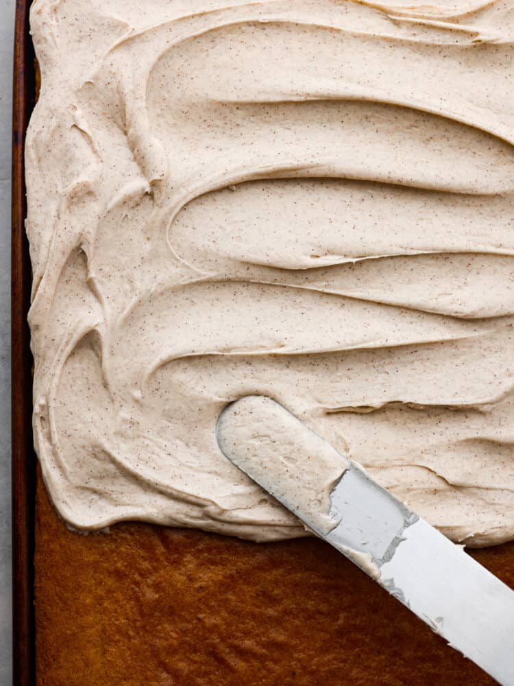 Whip up this simple cinnamon cream cheese frosting in less than 5 minutes! It's velvety smooth and once you add it to your cake or cupcakes for a delightful treat, everyone will be asking for seconds. The top view of a sheet cake with cinnamon cream cheese frosting.