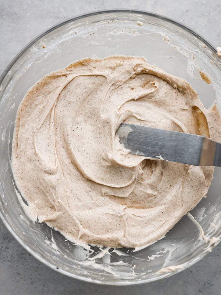 Whip up this simple cinnamon cream cheese frosting in less than 5 minutes! It's velvety smooth and once you add it to your cake or cupcakes for a delightful treat, everyone will be asking for seconds. The top view of a glass bowl with cinnamon cream cheese frosting.