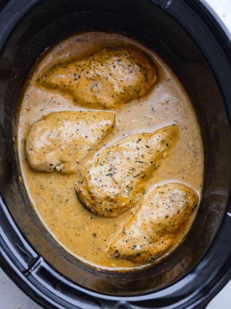 Whip up a comforting meal with this delicious Crockpot Chicken and Gravy recipe. Cooked to perfection in the slow cooker, the result is tender, juicy chicken smothered in a rich gravy, making it the perfect companion to rice or potatoes for a hearty and satisfying dinner! A top view of chicken and gravy in a crockpot.
