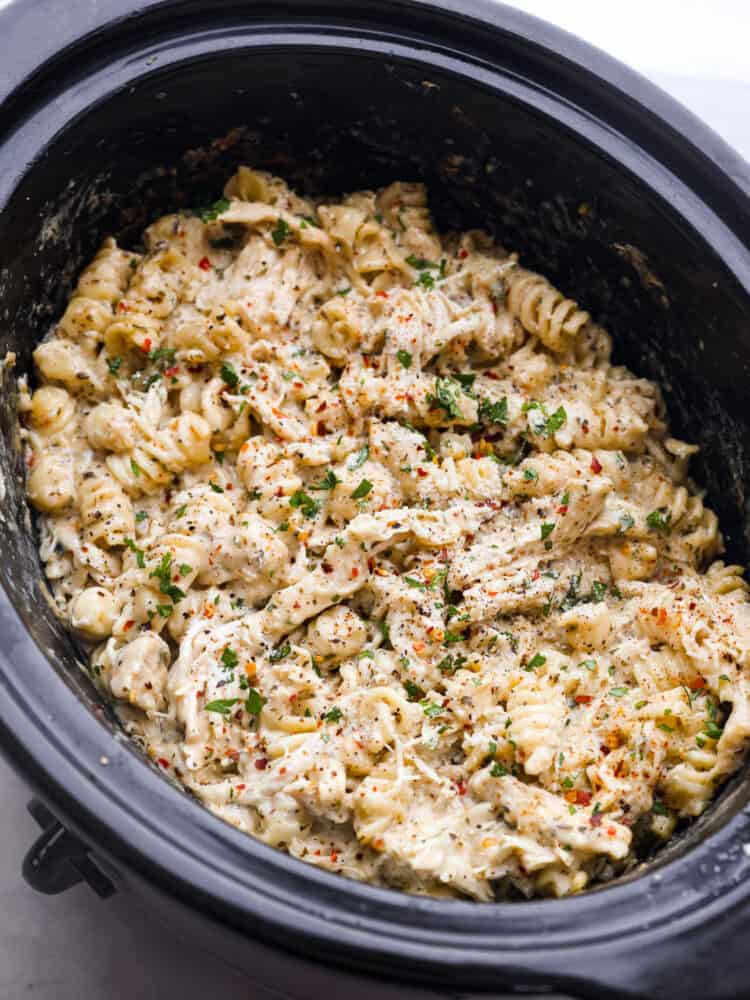 If you're looking for a knockout dinner that the whole family will love, this crockpot parmesan garlic chicken pasta is the recipe to try. It's so flavorful and satisfying, everyone will be licking their plates clean! It's easy, cheesy, and packed with mouthwatering garlic flavor. Cooked parmesan garlic chicken pasta in a crockpot.