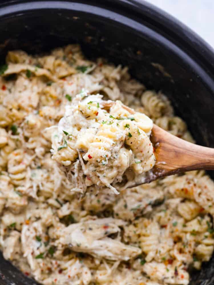 If you're looking for a knockout dinner that the whole family will love, this crockpot parmesan garlic chicken pasta is the recipe to try. It's so flavorful and satisfying, everyone will be licking their plates clean! It's easy, cheesy, and packed with mouthwatering garlic flavor. Closeup of a spoonful of crockpot parmesan garlic chicken pasta.