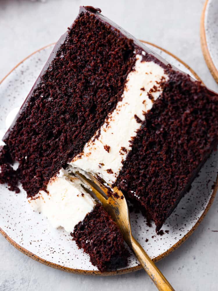 Ding Dong cake is the upgraded version of your favorite snack cakes, featuring a moist chocolate cake with a creamy ermine filling and a mouthwatering chocolate ganache on top! It's a seriously tasty dessert you won't be able to resist! Taking a bite of cake with a golden fork.