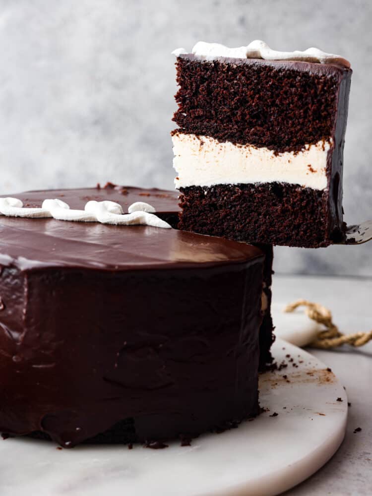 Ding Dong cake is the upgraded version of your favorite snack cakes, featuring a moist chocolate cake with a creamy ermine filling and a mouthwatering chocolate ganache on top! It's a seriously tasty dessert you won't be able to resist! A slice of Ding Dong cake being served.