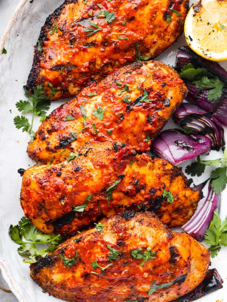 Harissa chicken is tender, juicy, and coated in a spicy, flavor-packed sauce that will leave your mouth watering. This easy and delicious North African dish is the perfect recipe to add to the dinner lineup this week! Closeup of harissa chicken.