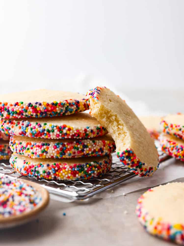 Icebox cookies are the best! They're these yummy treats made with butter, sugar, and vanilla that get even better when you chill the dough before baking. They're crispy on the outside and soft and tender on the inside. You'll be hooked after the first bite! A stack of 4 cookies. One cookie is laying up against them with a bite taken out of it.