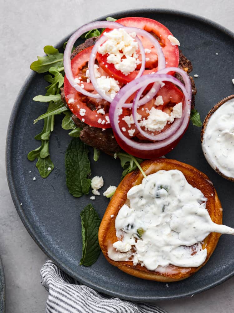 Make these amazing lamb burgers to add a Greek twist to your next summer barbecue! Top-down view of a lamb burger, with the top bun removed.