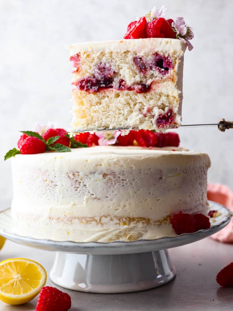 Introducing the ultimate summer dessert: lemon raspberry cake! Zesty lemon layers, juicy raspberries, and creamy lemon frosting make this a must-try dessert. It's impressive, delicious, and everyone will want a slice. A slice of cake being served.