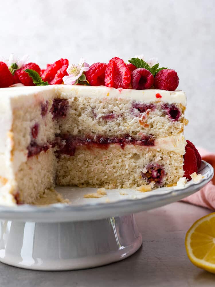 Introducing the ultimate summer dessert: lemon raspberry cake! Zesty lemon layers, juicy raspberries, and creamy lemon frosting make this a must-try dessert. It's impressive, delicious, and everyone will want a slice. Lemon raspberry cake with a slice taken out of it.