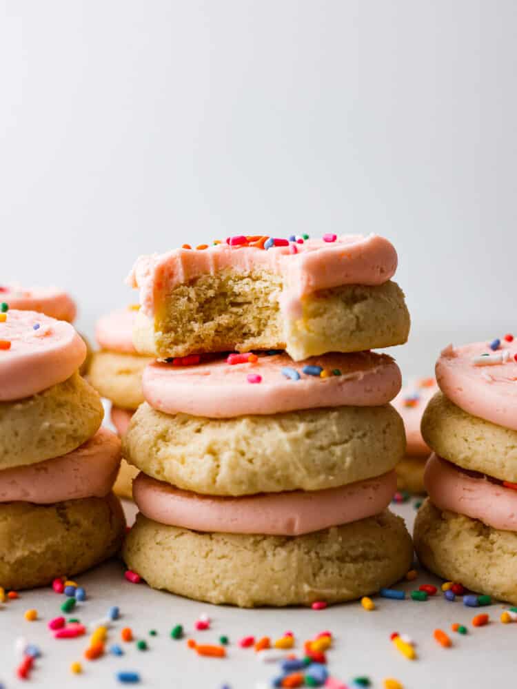 These classic Lofthouse Sugar Cookies are soft and puffy cake-like sugar cookies that taste just like the original! Topped with homemade buttercream frosting and rainbow sprinkles, these cookies will bring your right back to your childhood! A stack of lofthouse style sugar cookies.