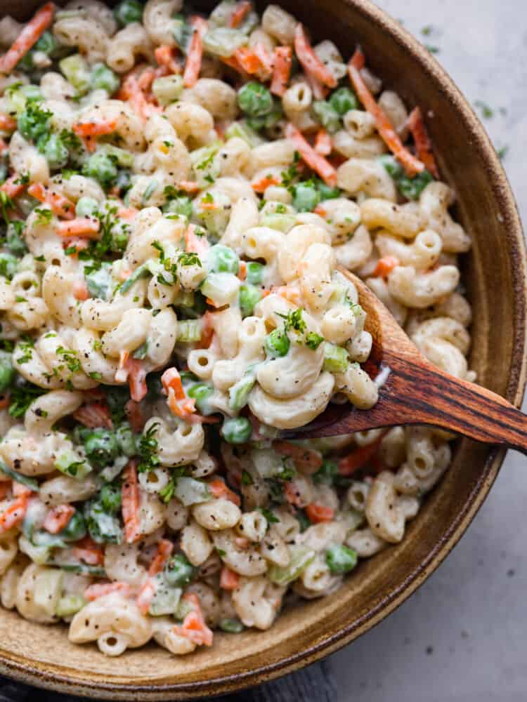 This easy macaroni salad is a potluck superstar! It's creamy and flavorful with peas, carrots, and celery added in for some extra color and crunch. Each bite is a dream! Closeup of easy macaroni salad in a serving bowl.