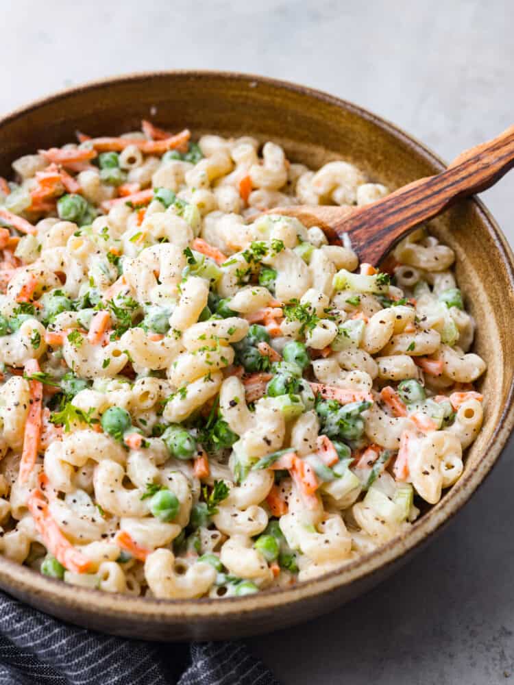 This easy macaroni salad is a potluck superstar! It's creamy and flavorful with peas, carrots, and celery added in for some extra color and crunch. Each bite is a dream! Pasta salad in a serving bowl.