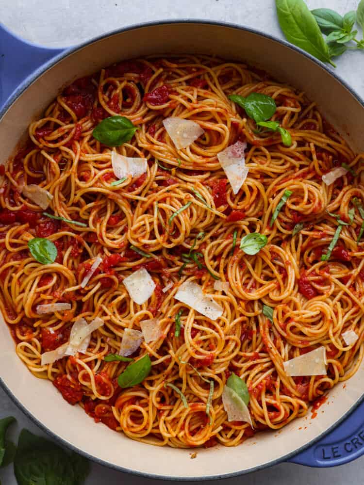 Experience the delicious taste of Italy with this easy Pasta Pomodoro recipe. Cook the pasta and make a flavorful tomato sauce with shallots, garlic, and a hint of red pepper flakes. Top it off with melted parmesan cheese and fresh basil for a mouthwatering dish that will leave you wanting more! The top view of a pot of pasta pomodoro garnished with fresh cheese and mozzarella.