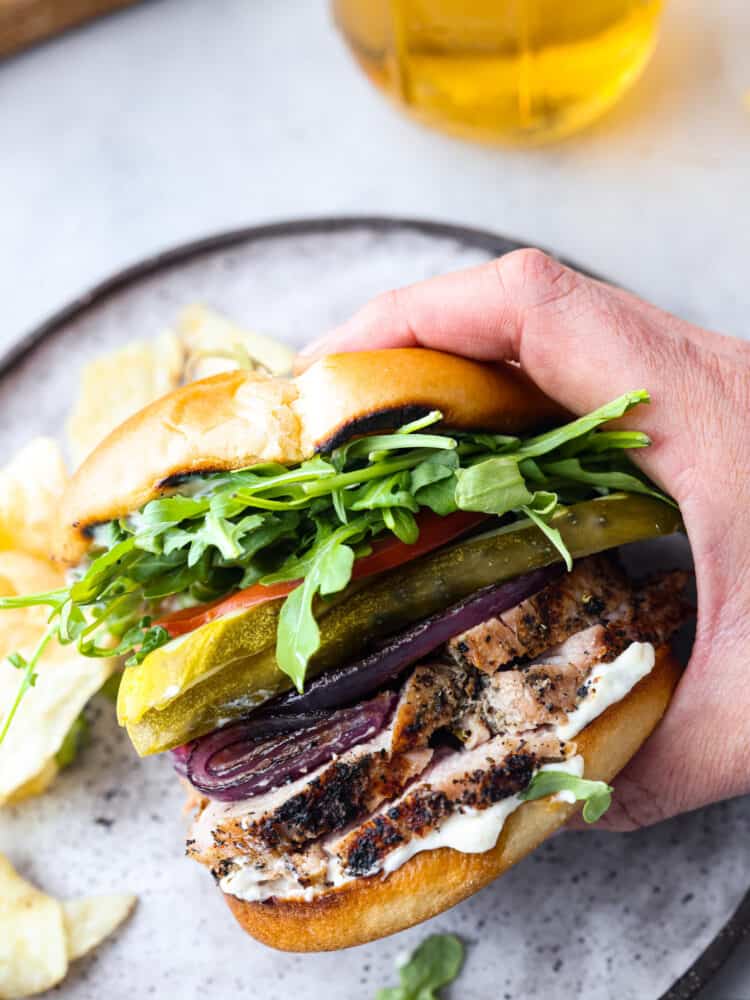 A homemade pork tenderloin sandwich is the perfect hearty lunch! A pork tenderloin sandwich being picked up.