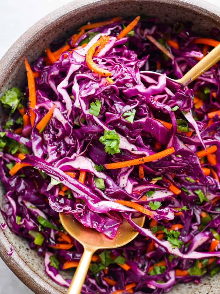 Who would've thought that red cabbage slaw could be so dang tasty? Trust me, this stuff is delicious! Finely sliced red cabbage, matchstick carrots, and herbs tossed with a killer dressing made of olive oil, lime juice, honey, and garlic. It’s the perfect way to jazz up any dish. Closeup of red cabbage slaw.