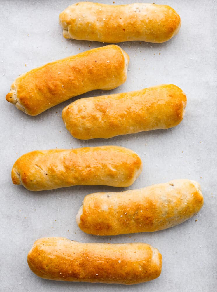 Runza is a tasty, handheld pastry stuffed with a scrumptious mix of ground beef, onions, garlic, cabbage, and spices, all snug inside soft pizza dough. Top-down view of 6 cooked runza.