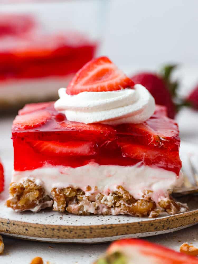 Strawberry Pretzel Salad has a sweet and salty pretzel crust, cream cheese middle, and a jello strawberry layer on top. Perfection!ย Everyone loves this salad! Closeup of strawberry pretzel salad.