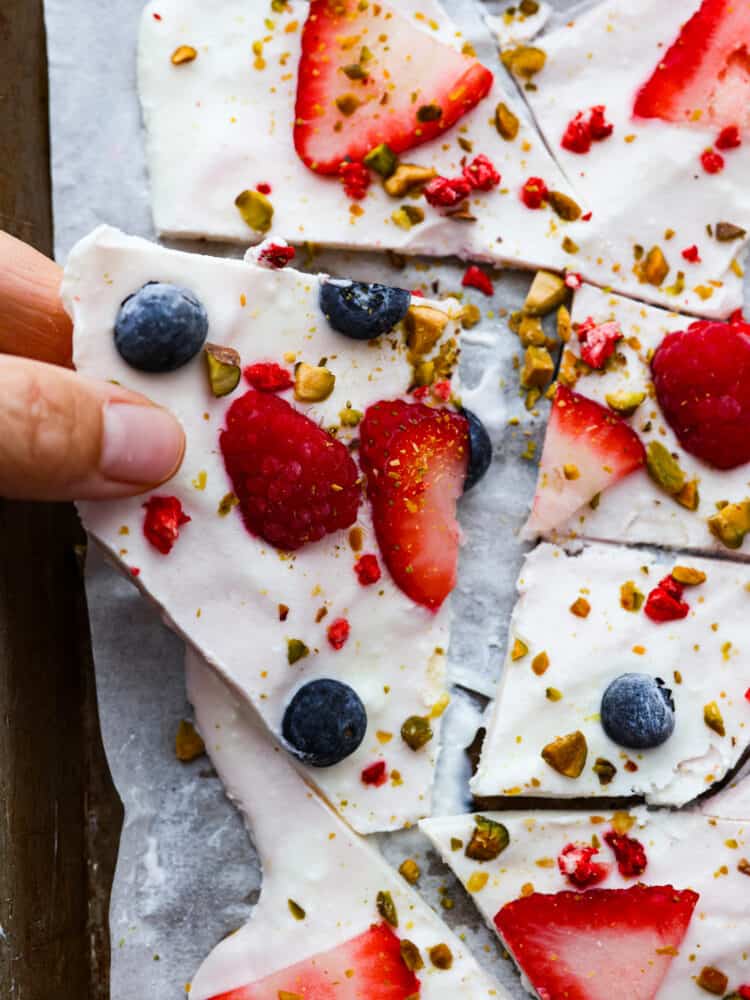 Frozen yogurt bark is SO easy to make and beyond delicious! Load it up with your favorite toppings for a summer treat that’s both tasty and healthy. Picking up a piece of frozen yogurt bark.