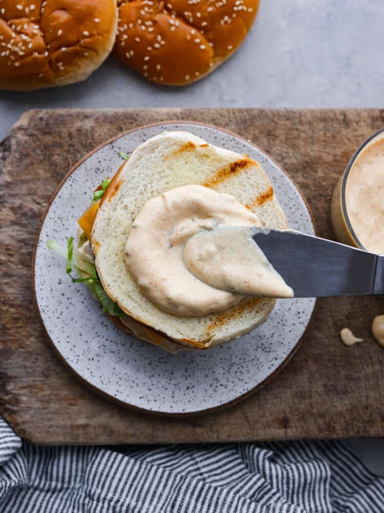 Two juicy all-beef patties, special sauce, lettuce, cheese, pickles, and onions all on sesame seed buns! You'll love recreating this copycat Big Mac burger at home. Spreading Big Mac sauce onto a bun.