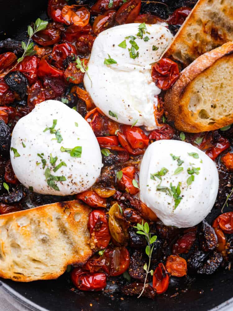 This burrata appetizer is a flavor bomb made with juicy cherry tomatoes, sweet dried figs, and a tangy balsamic kick. Topped with creamy burrata cheese, it's pure indulgence. Perfect for parties or whenever you want to treat yourself to something special! Closeup of a tomato and burrata appetizer.