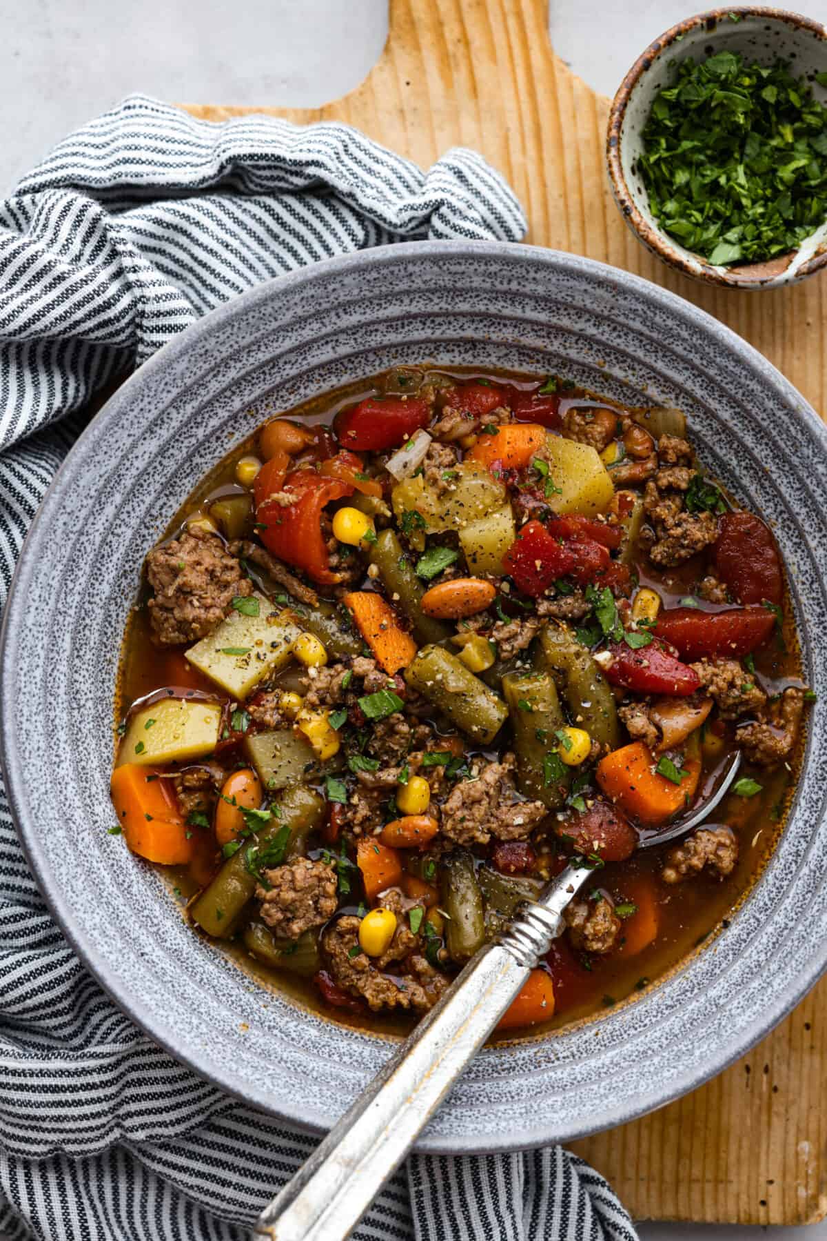 Experience the wild west in a bowl with this Cowboy Hamburger Soup recipe! This comforting blend features seasoned ground beef, veggies, and a touch of Tex-Mex, simmered to perfection in a hearty beef broth. A bowl of cowboy hamburger soup.