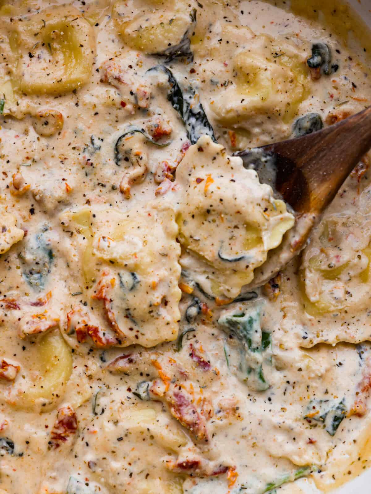 Indulge in this creamy Tuscan ravioli made with the most mouthwatering sun-dried tomato sauce! It's one of the best pasta dishes you'll make, and it's ready in less than 30 minutes. The perfect dinner for busy weeknights! Closeup of creamy Tuscan ravioli.