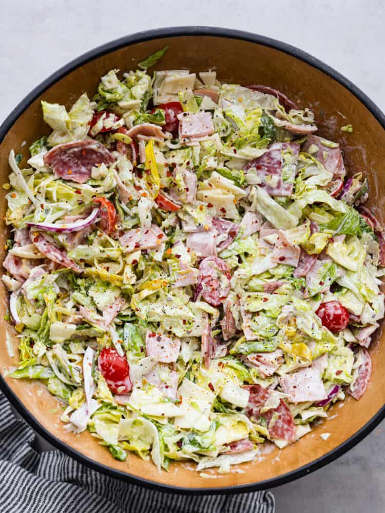 This grinder salad is a deconstructed version of the classic sandwich, made with lettuce, brussels sprouts, salami, ham, provolone, and fresh veggies. It’s all coated in a creamy, savory dressing that you won’t be able to get enough of! Hero image of grinder salad in a serving bowl.