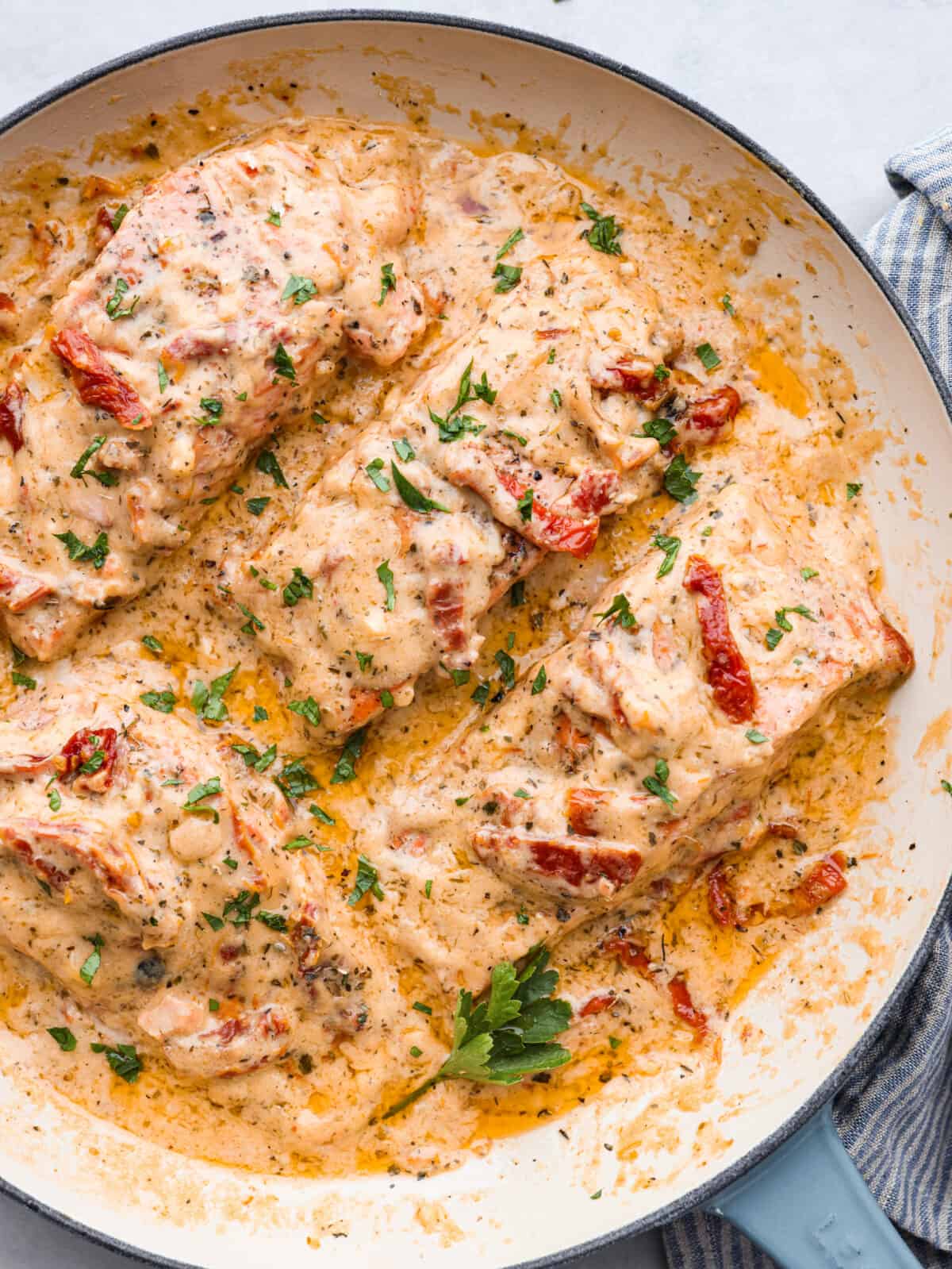 Salmon so good, it will have everyone falling in love! Marry Me Salmon is soft and flaky, smothered in a buttery, creamy sun-dried tomato sauce. Trust me, itโs one of the best dishes youโll ever make! Top-down view of marry me salmon in a white and blue skillet.