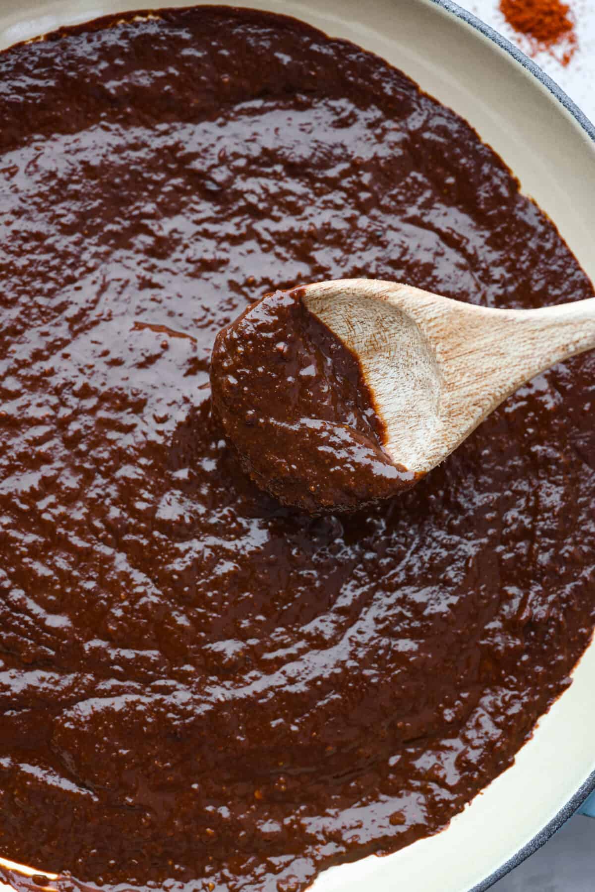 Meet mole, the Mexican sauce that's a tasty blend of spices, from cumin's earthiness to chipotle's kick. What really sets it apart is the touch of cocoa powder added for a little sweet richness. It's the best blend of flavors, you're going to love it! Closeup of mole sauce being stirred with a wooden spoon.