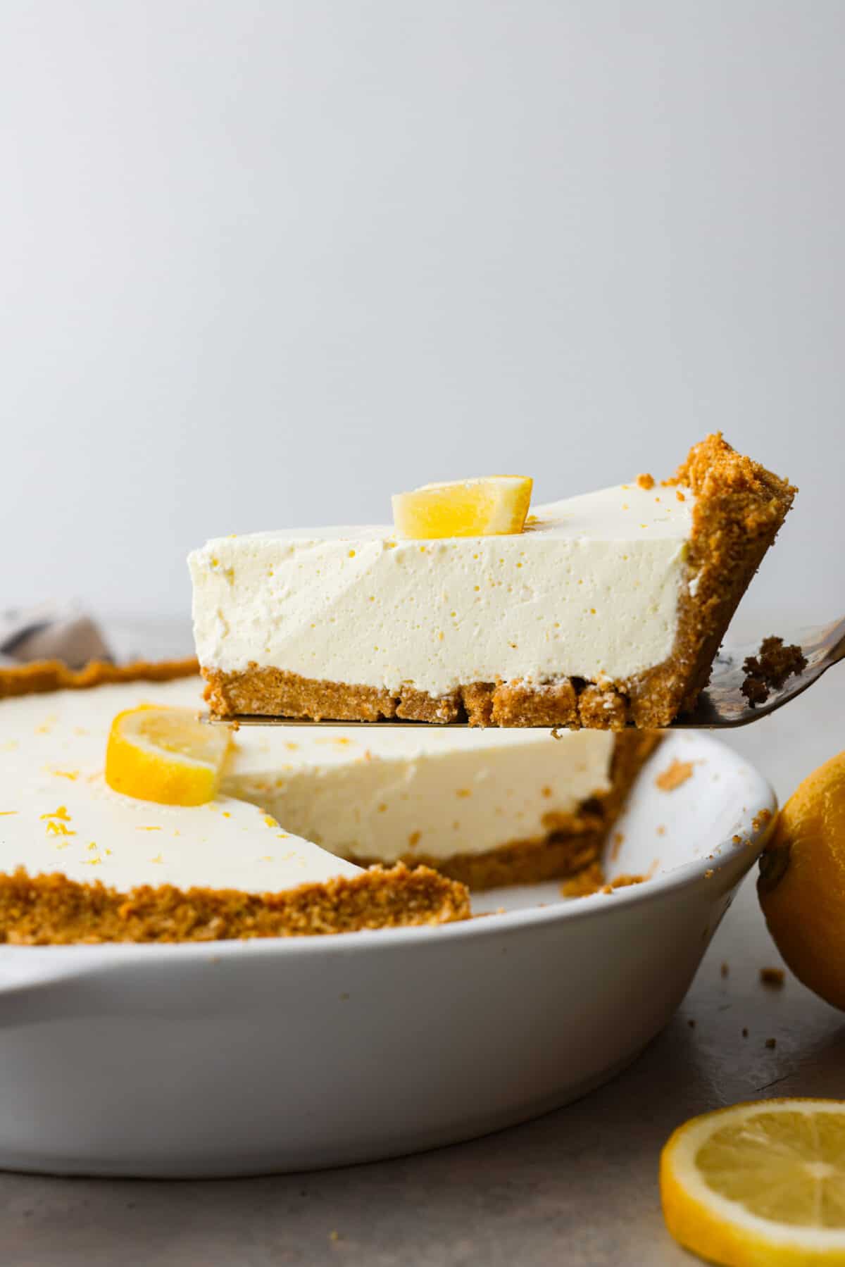 No-bake lemon pie is a light and creamy pie bursting with refreshing lemony flavor. It's sweet and zingy all at the same time! This pie is easy to make and is the perfect spring or summer dessert! Close side view of a piece of pie being lifted up with a spatula.