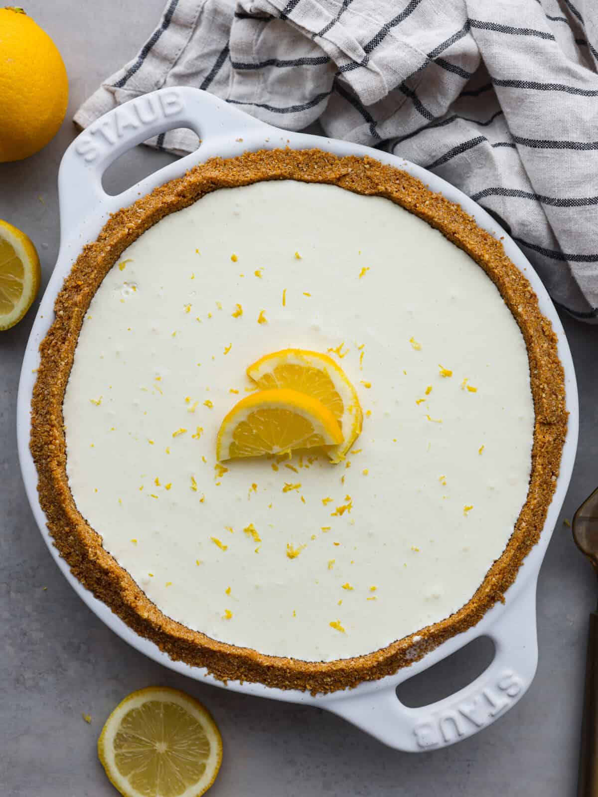 No-bake lemon pie is a light and creamy pie bursting with refreshing lemony flavor. It's sweet and zingy all at the same time! This pie is easy to make and is the perfect spring or summer dessert! Top view of the whole no-bake lemon pie garnished with lemon slices.