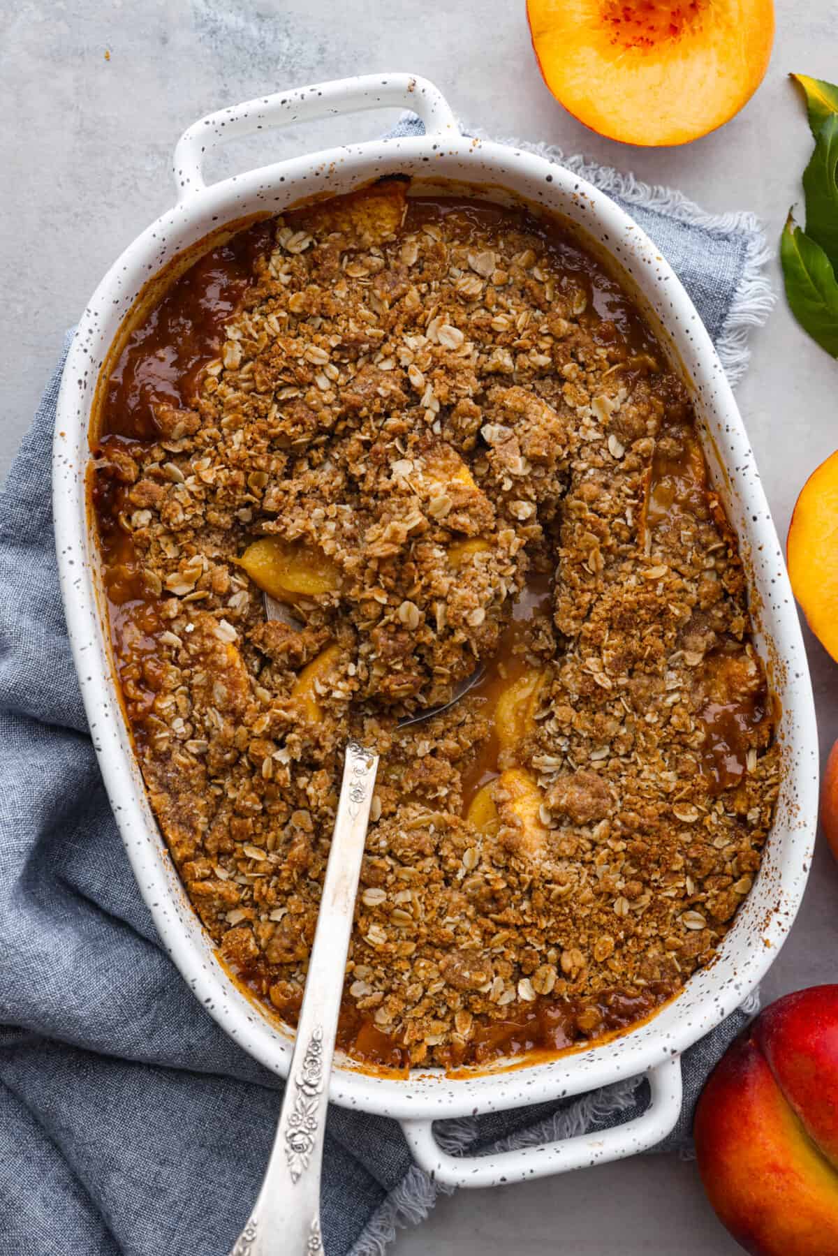 Celebrate summer with a mouthwatering Peach Crisp! Juicy peaches, sweet cinnamon, and a crunchy topping come together for a delightful treat that's perfect when it's served warm with a scoop of vanilla ice cream! The top view of a peach crisp in a 9x13 dish.
