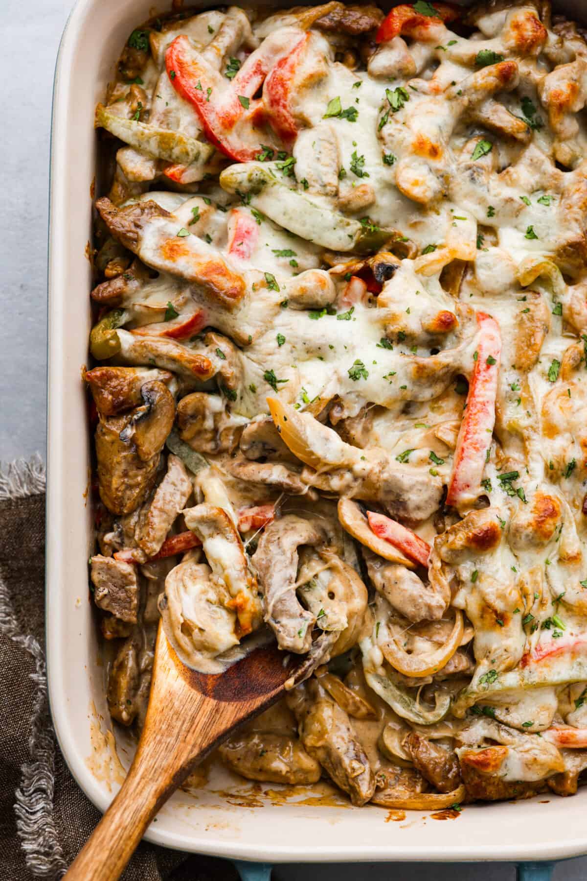 Try this delicious Philly Cheesesteak Casserole, a twist on the classic Philly Cheesesteak. Tender sirloin steak, colorful veggies, and creamy cheese come together for a mouthwatering meal the whole family will love! The top view of Philly Cheesesteak casserole in a 9x12 baking dish.