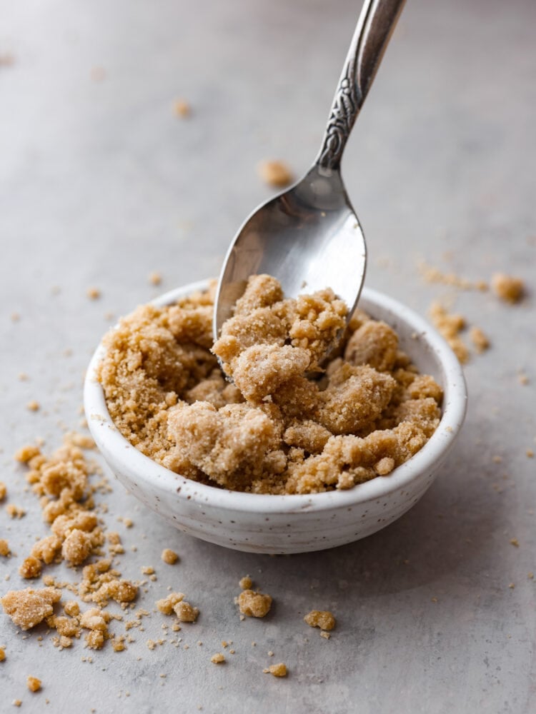 Elevate your treats with this easy Streusel Topping recipe! Whether you sprinkle it before baking or bake it separately for a sweet crunch, it's a tasty twist your baked goods will love! A spoon scooping out some streusel topping.