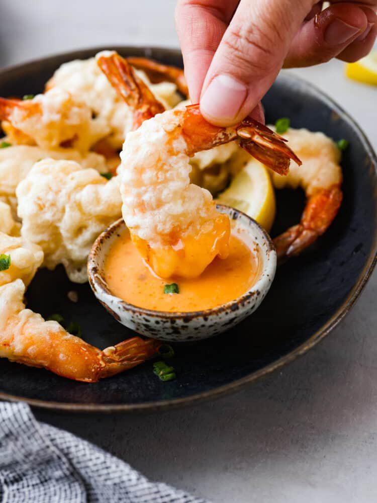 Lightly battered and fried to golden perfection, this shrimp tempura is the perfect dish for any seafood lover! One bite of its crispy goodness and you'll be hooked. Picking up a piece of tempura shrimp.